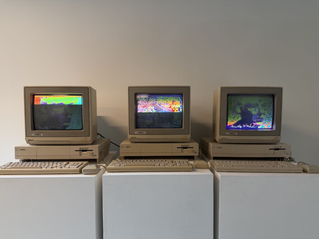 Vintage computers displaying original 1985 Andy Warhol digital art pieces exploring early digital creativity.