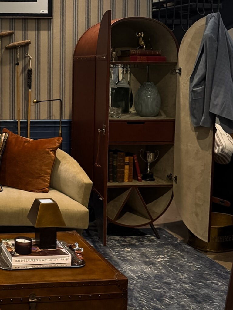 Tall arched cabinet with books and decorative objects inside Yates Desygn’s A Private Affair vignette at Dallas Market Center